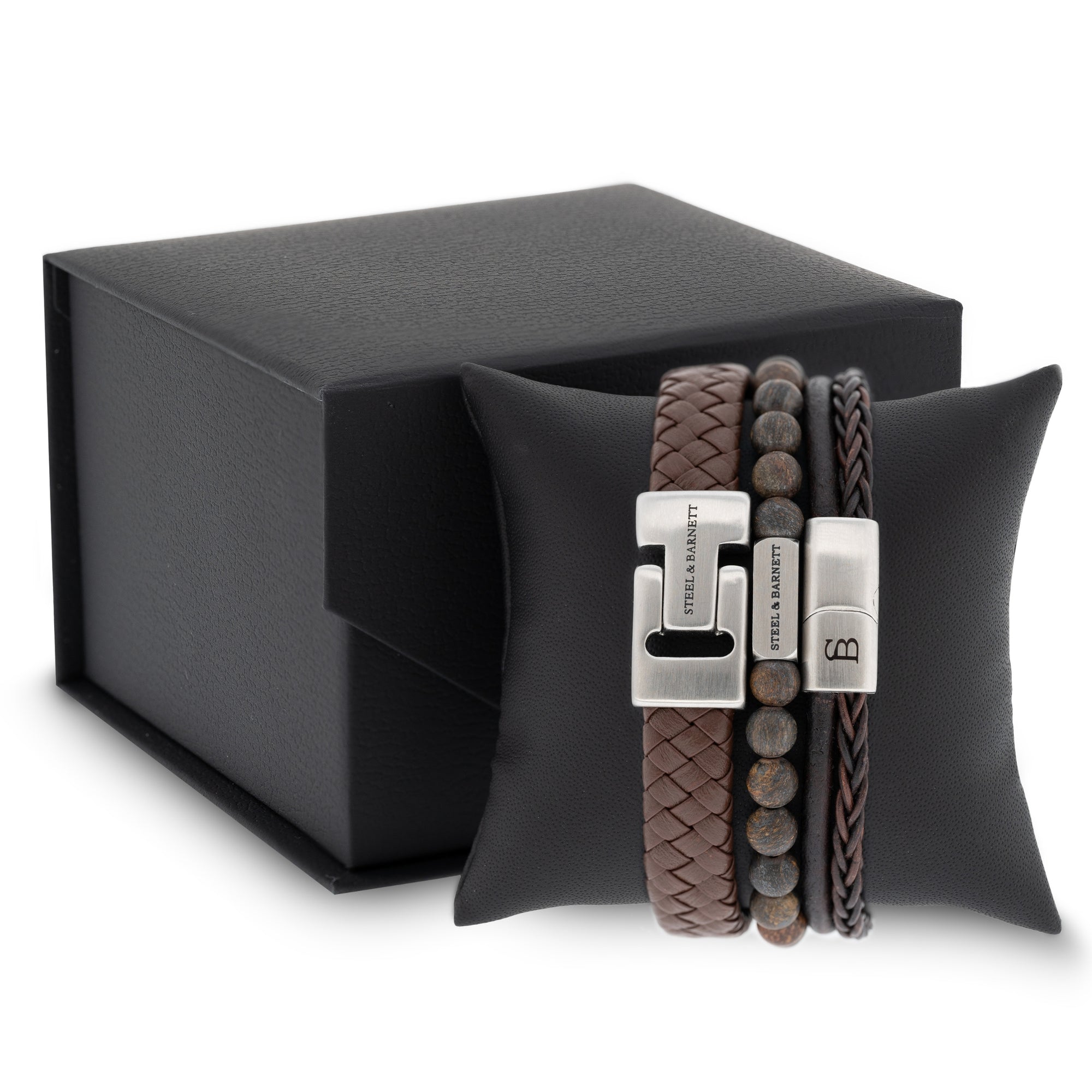 stacked men’s brown leather bracelets with braided leather and natural stone beads displayed on a black cushion next to a gift box