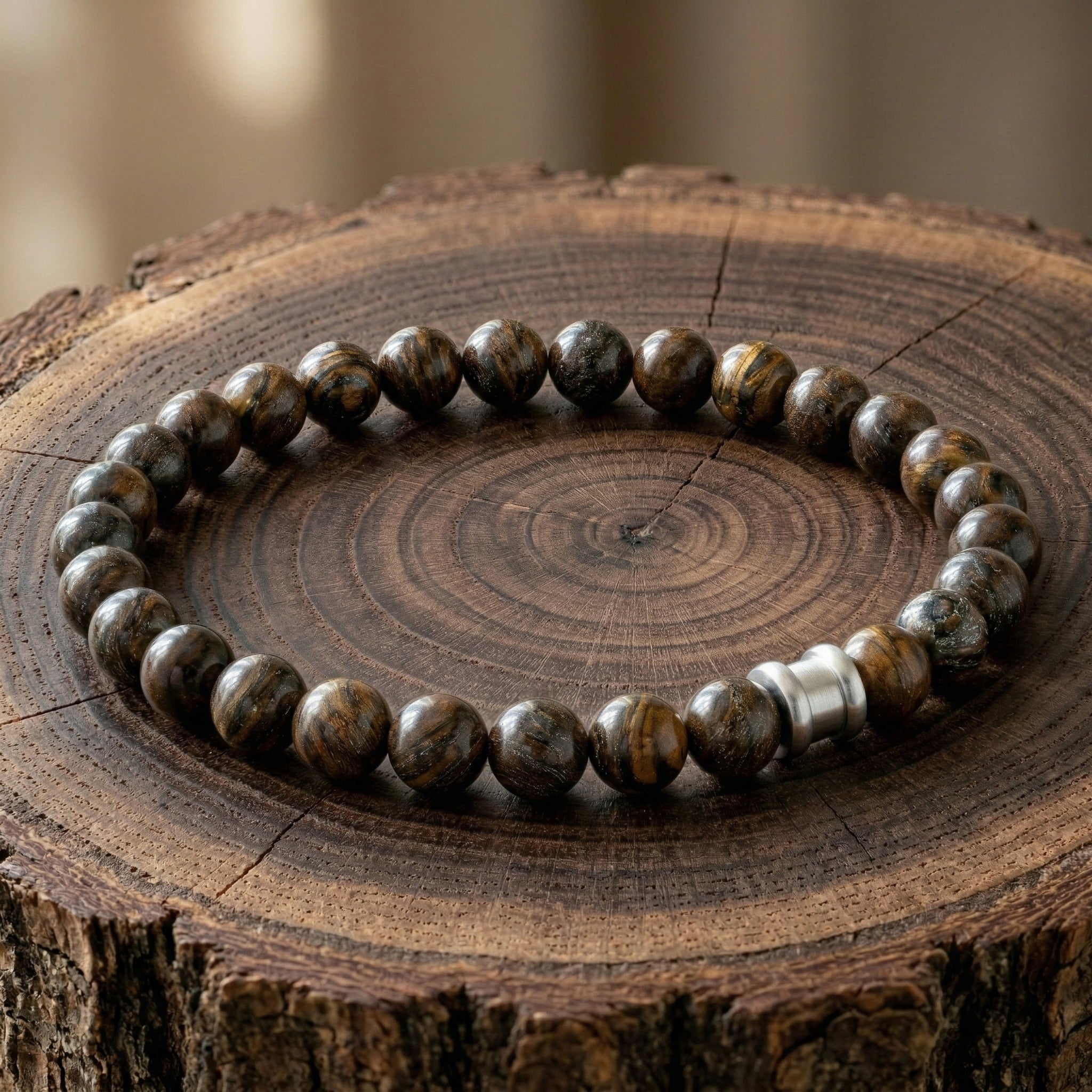 Brown tiger eye men’s bracelet with round polished beads and stainless steel accent on a wooden surface