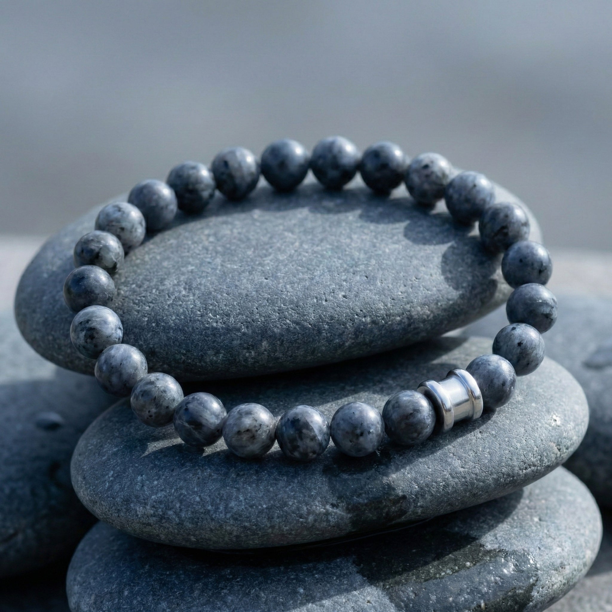 Grey labradorite men’s bracelet with round matte gemstone beads and stainless steel accent on stacked stone surface