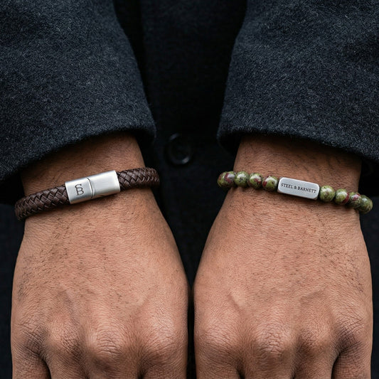 Brown braided leather men's bracelet with stainless steel clasp paired with green beaded gemstone bracelet in a stacked look on wrist