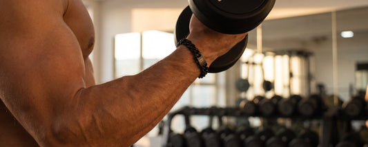 Black chain men's bracelet with a dark metal clasp worn on the wrist while lifting a dumbbell in a gym