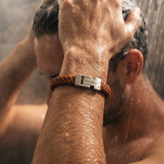 Brown leather men's bracelet with a silver stainless steel clasp is worn on a wrist under shower