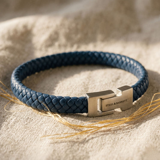 Blue braided leather bracelet with a metal clasp on a linen background