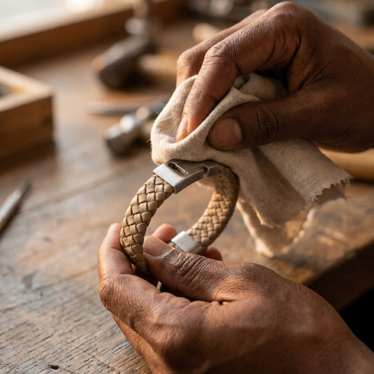 Brown braided leather men's bracelet with a brushed stainless steel magnetic clasp being cleaned by hand on a wooden workbench close up detail shot
