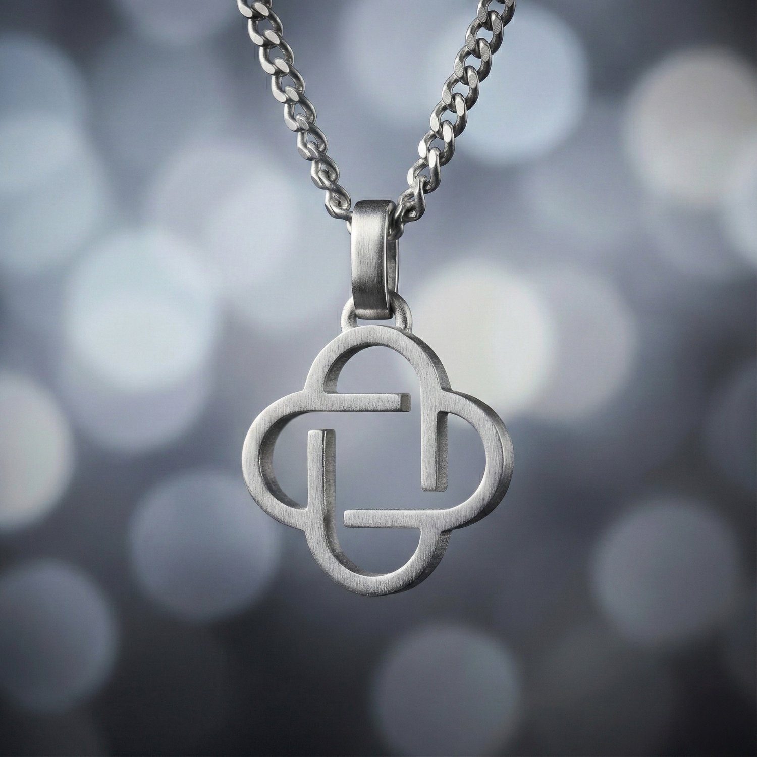 Silver necklace with a clover-shaped pendant against a blurred background
