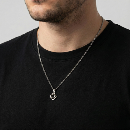Man wearing a black shirt with a silver necklace featuring a geometric pendant.