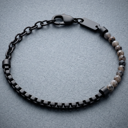 Black men's bracelet with matte stainless steel chain links, faceted grey stone beads and lobster clasp on stone surface