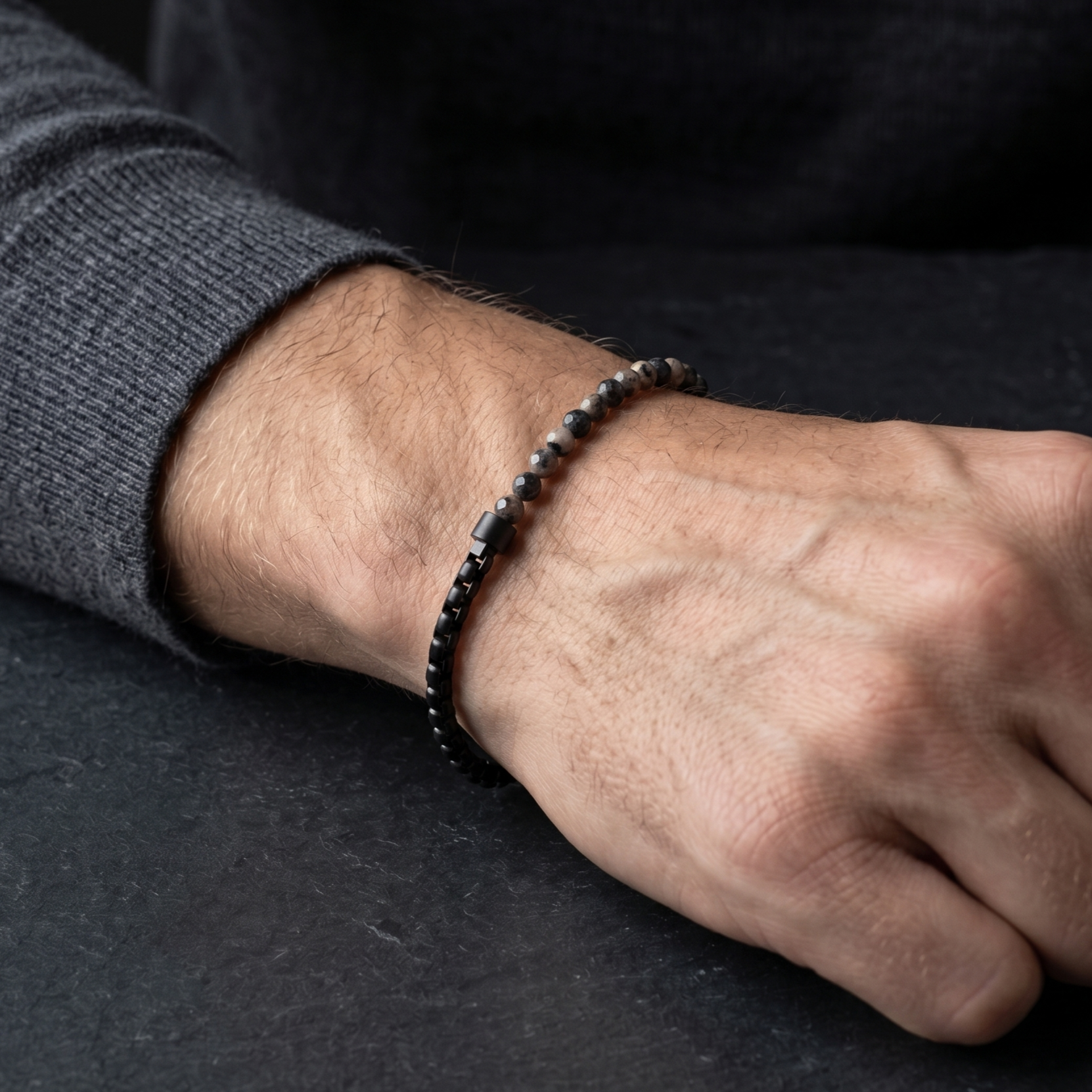 Black men's beaded bracelet with faceted natural stone beads and matte stainless steel chain detail shown on wrist