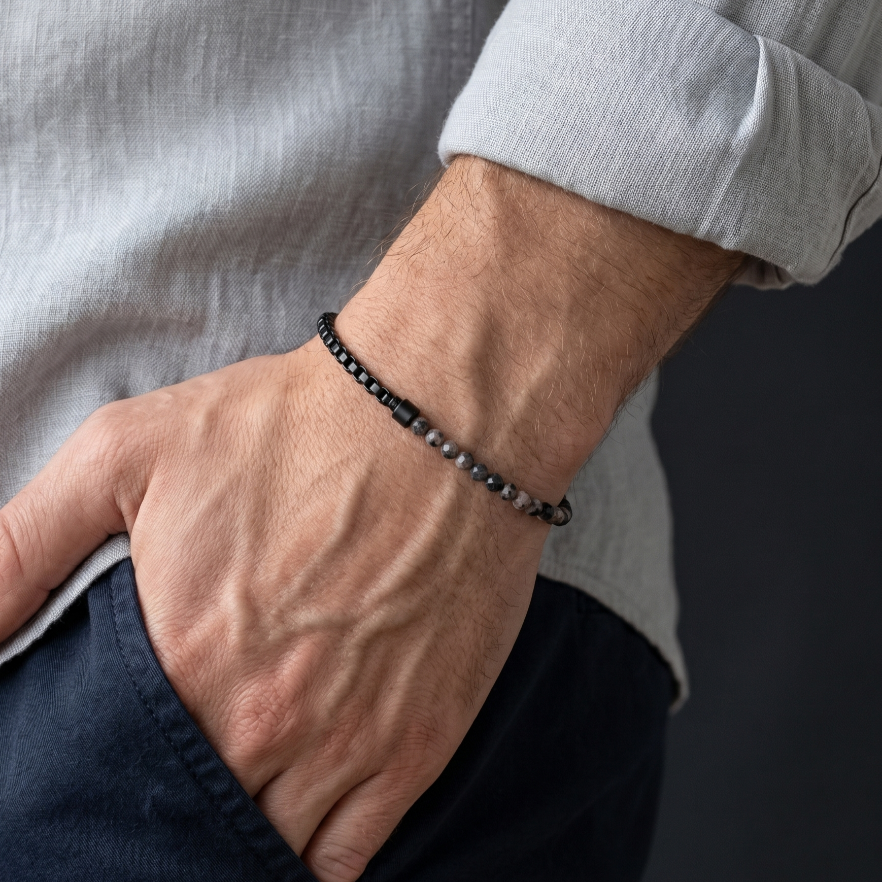 Black men's stainless steel and gemstone bracelet with minimalist chain design worn on wrist with casual styling