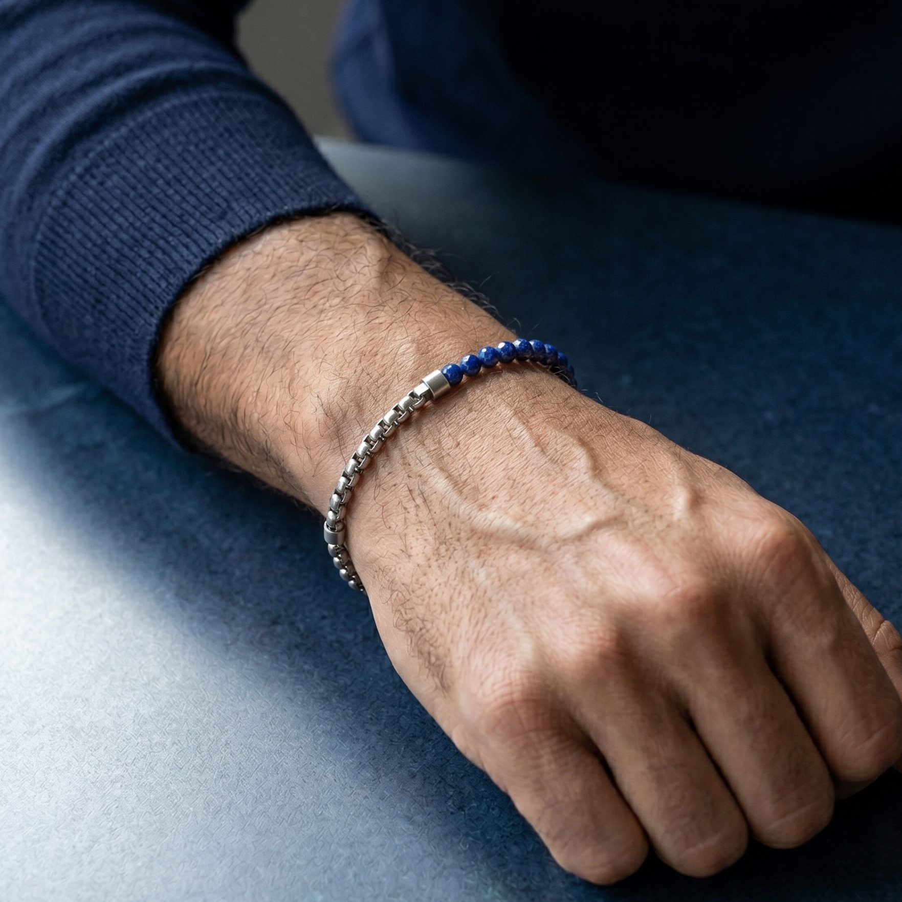 Silver men's stainless steel bracelet with blue faceted gemstone beads and minimalist chain detail worn on wrist