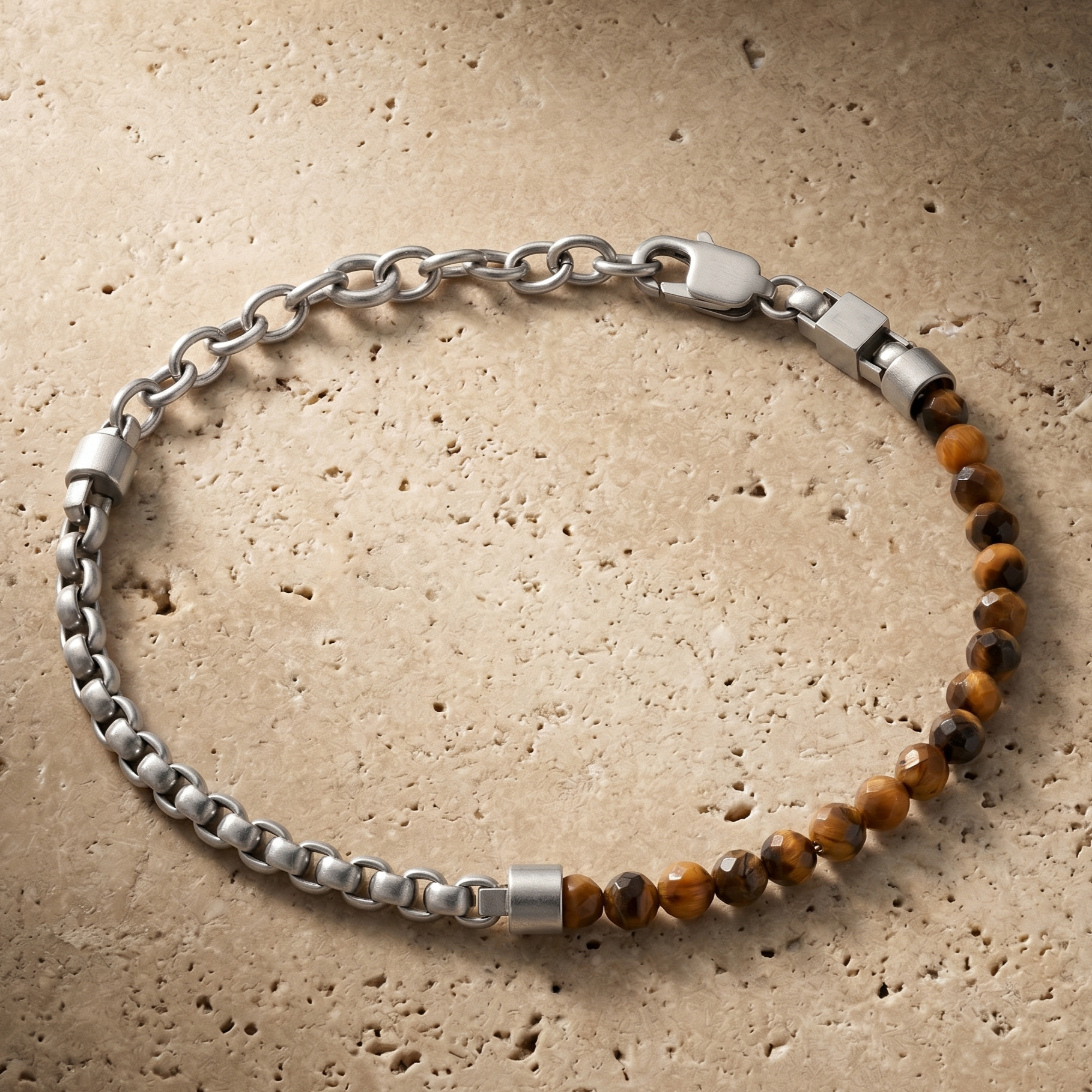 Silver men's bracelet with brushed stainless steel chain links, faceted tiger eye beads and lobster clasp on stone surface