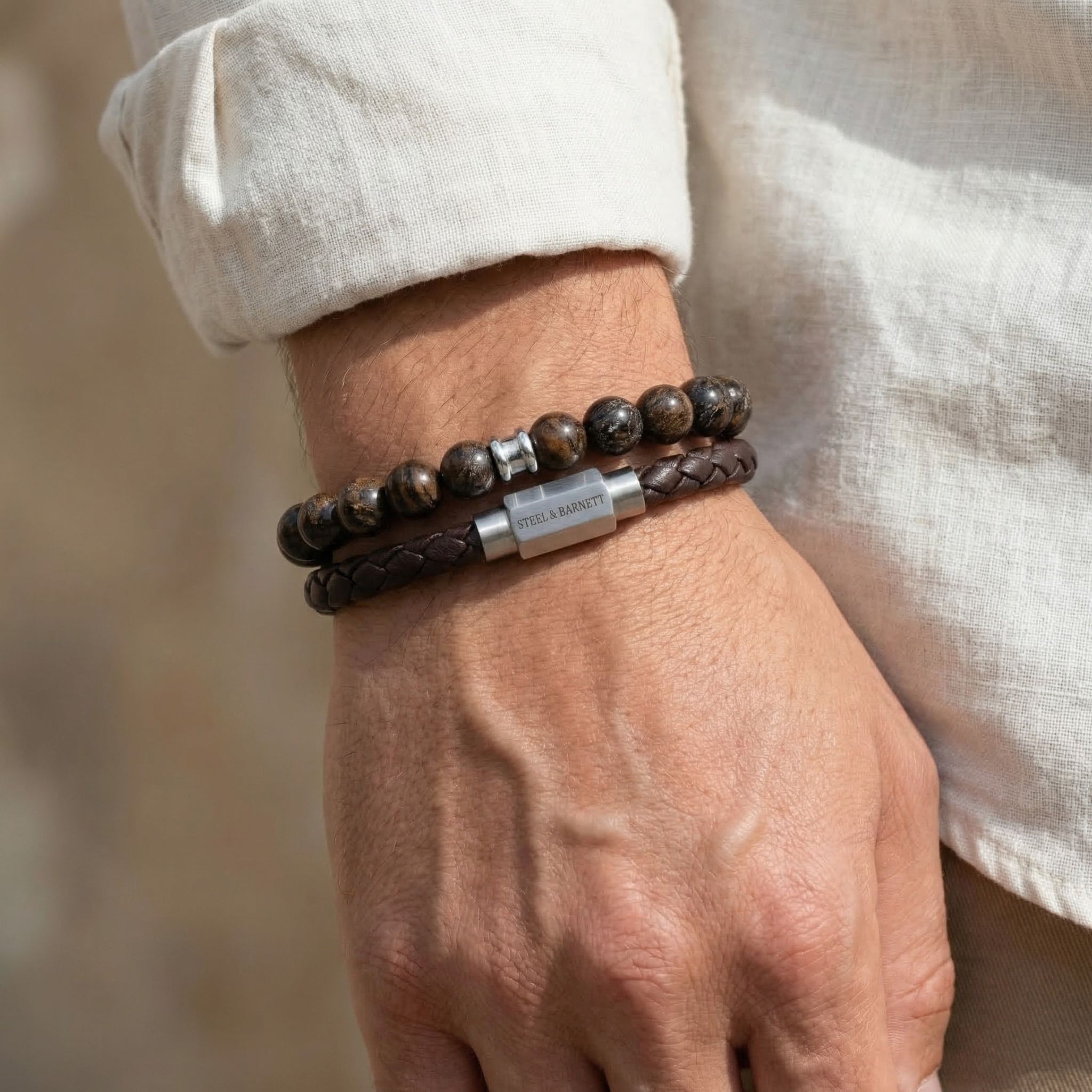 Brown natural stone and braided leather men's bracelets with stainless steel clasp worn in a stacked look on wrist