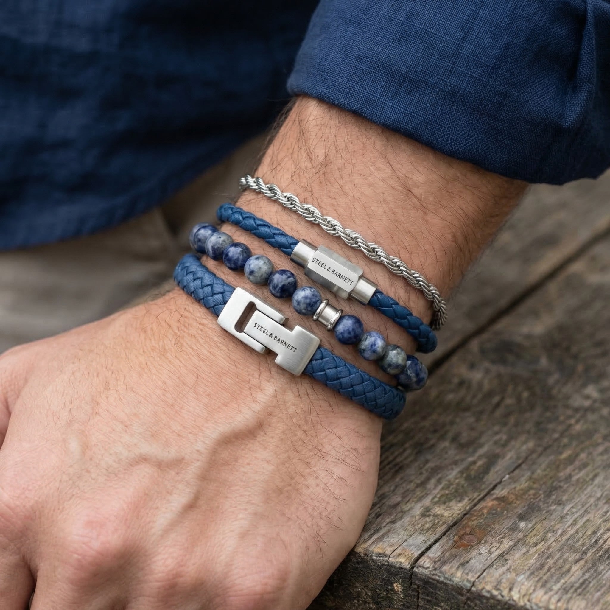Blue leather and natural stone men's bracelets with stainless steel clasps and silver chain worn in a stacked look on wrist