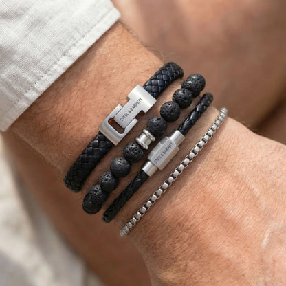 Black braided leather men's bracelet set with lava stone beads and stainless steel clasps in layered look on wrist