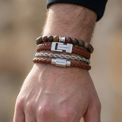 Brown braided leather men's bracelet set with multicolor gemstone beads and stainless steel clasps in layered look on wrist