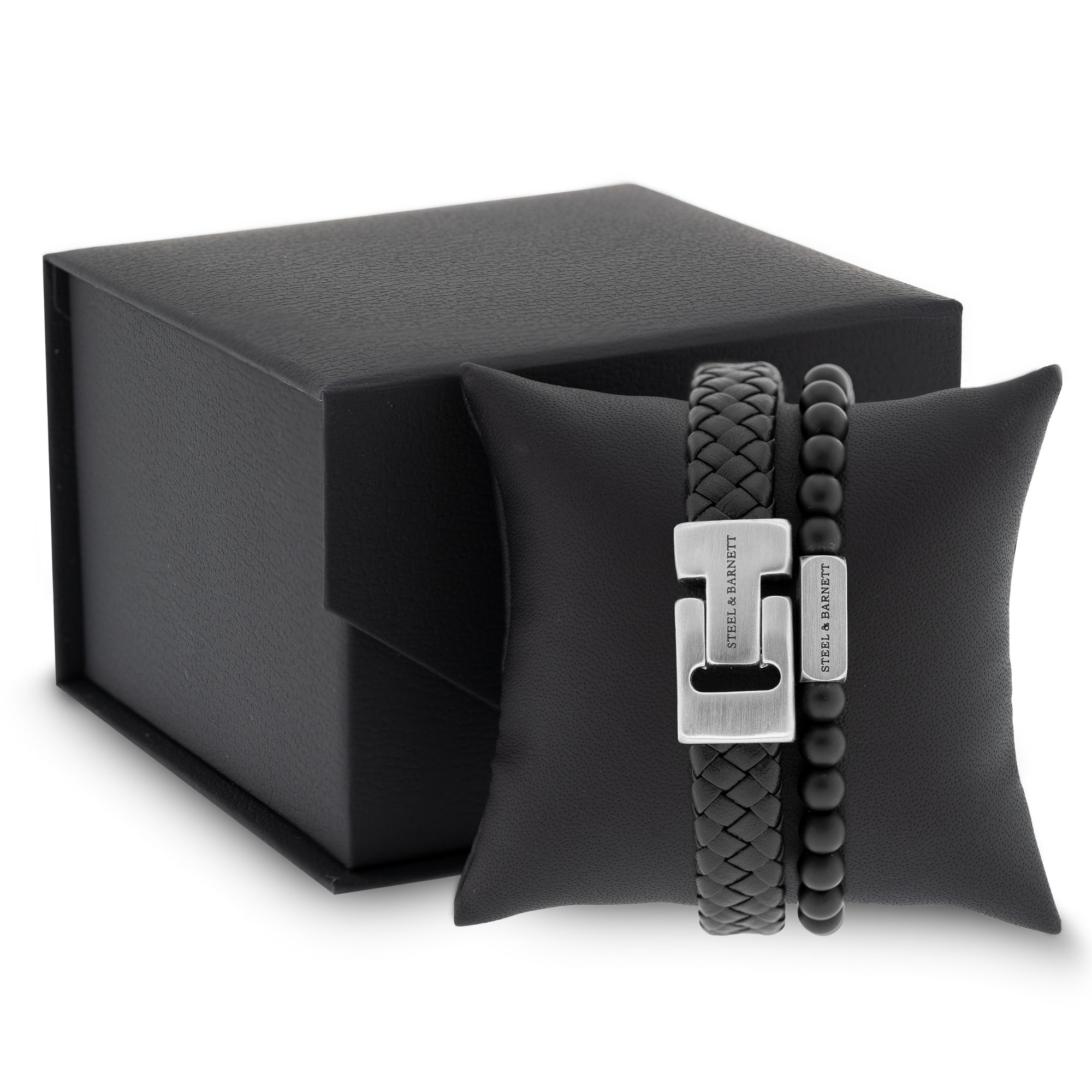 Black braided leather men's bracelet with brushed stainless steel clasp and beaded design displayed on a black cushion next to a gift box