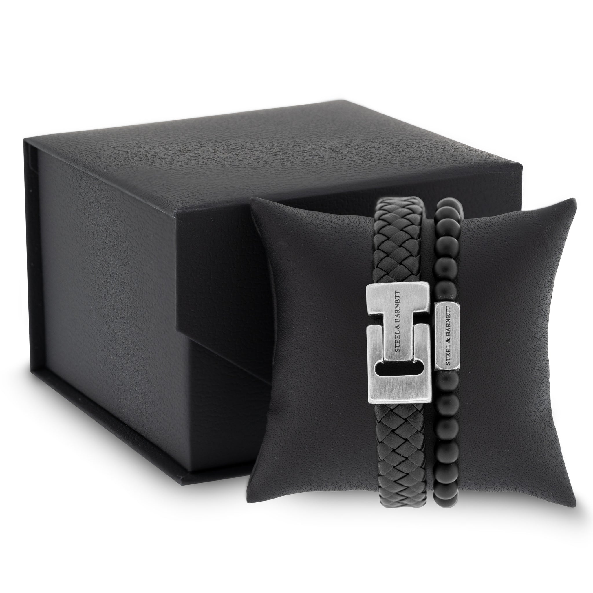 Black braided leather men's bracelet with brushed stainless steel clasp and beaded design displayed on a black cushion next to a gift box