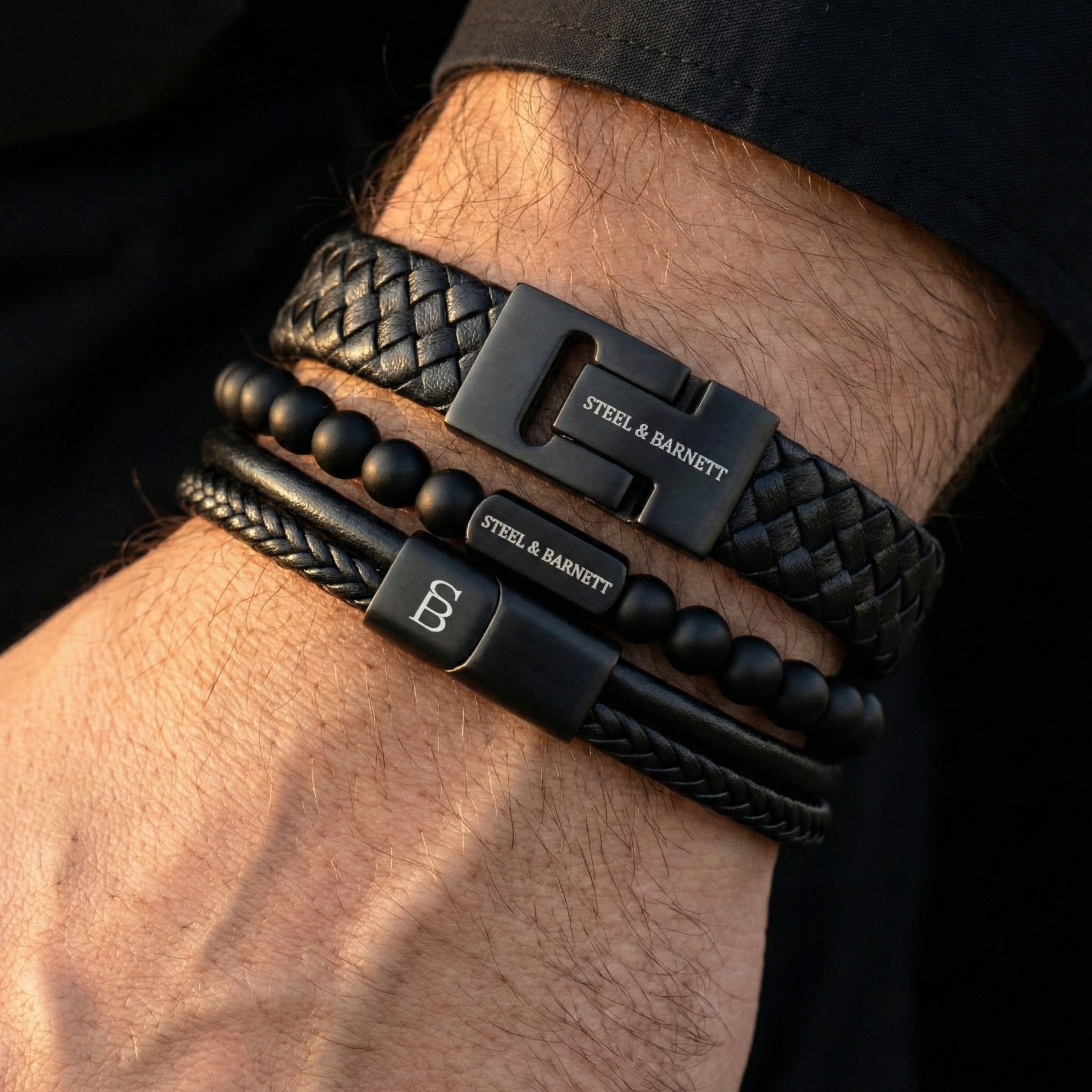 stacked black leather men’s bracelets with braided leather and matte beads featuring black stainless steel clasps shown on wrist in close-up
