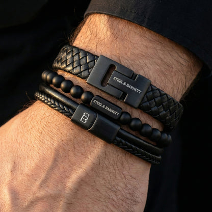stacked black leather men’s bracelets with braided leather and matte beads featuring black stainless steel clasps shown on wrist in close-up