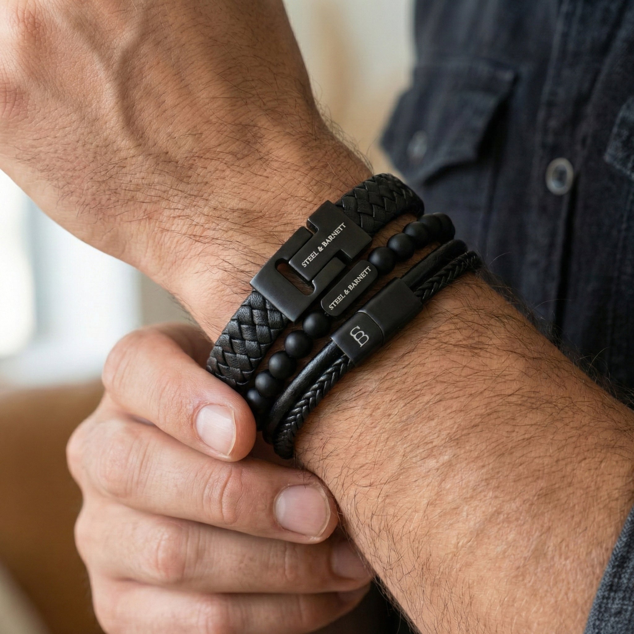 stacked black leather men’s bracelets with braided leather and matte bead details featuring black stainless steel clasps worn on wrist