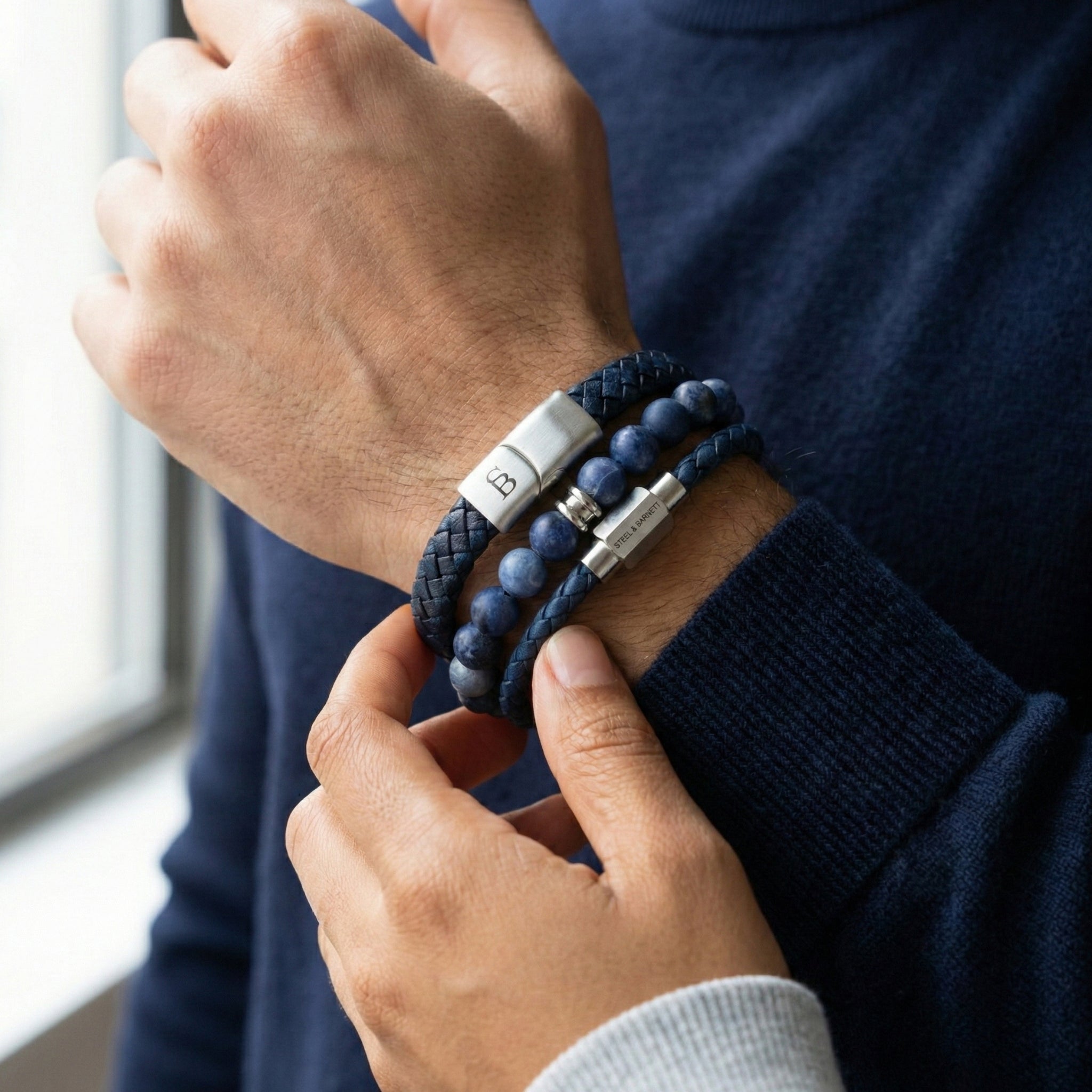 Layered blue leather men’s bracelet set with natural stone bead bracelet and brushed stainless steel clasps worn on wrist indoors