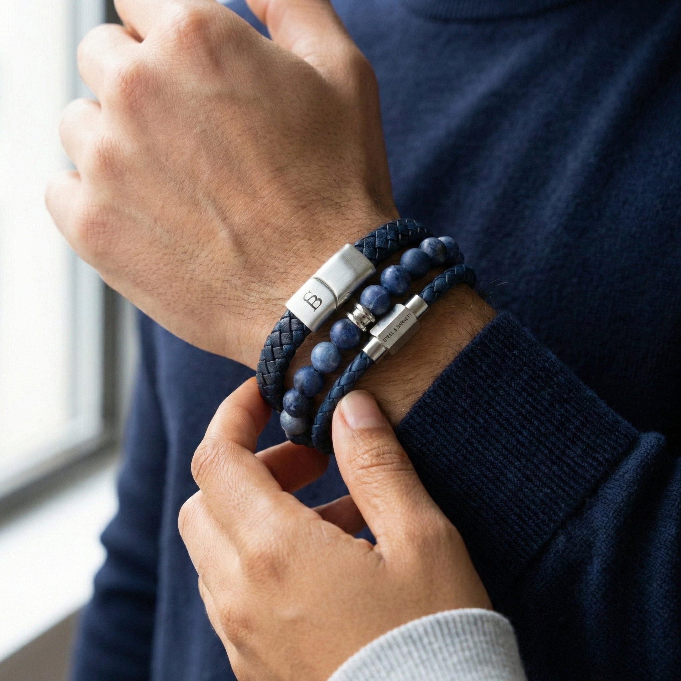 Layered blue leather men’s bracelet set with natural stone bead bracelet and brushed stainless steel clasps worn on wrist indoors