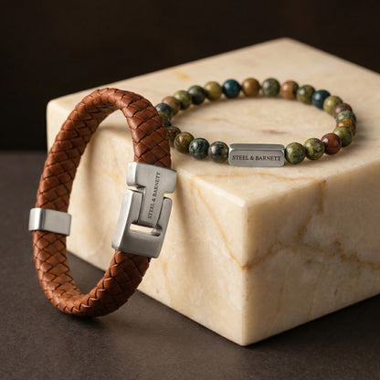 Brown braided leather men’s bracelet with brushed stainless steel clasp and matching natural stone bead bracelet shown in a close up on a light stone surface