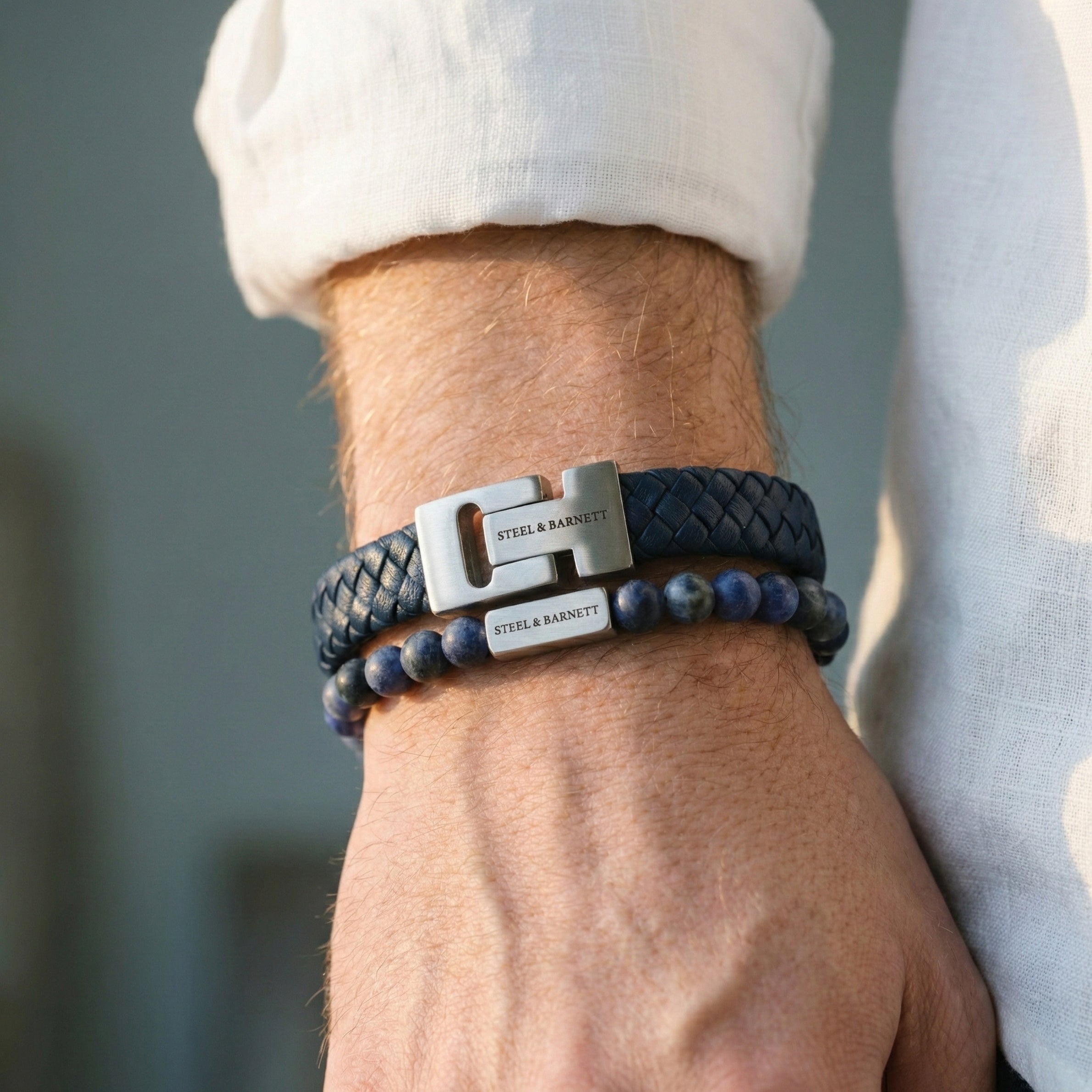 Blue braided leather men’s bracelet with brushed stainless steel clasp and beaded design worn on wrist in natural light