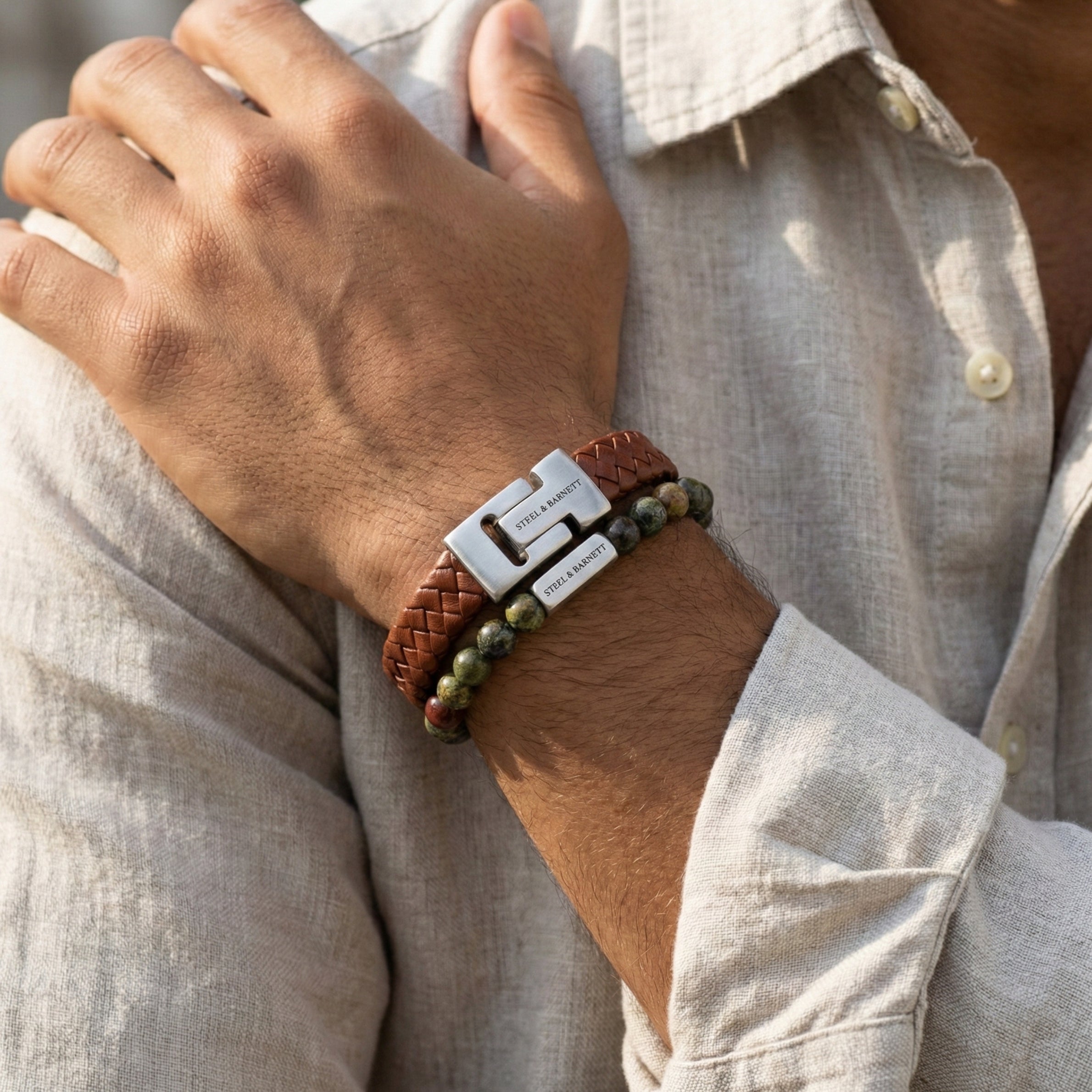 Brown braided leather men’s bracelet with brushed stainless steel clasp and natural stone beads worn on wrist in a model shot