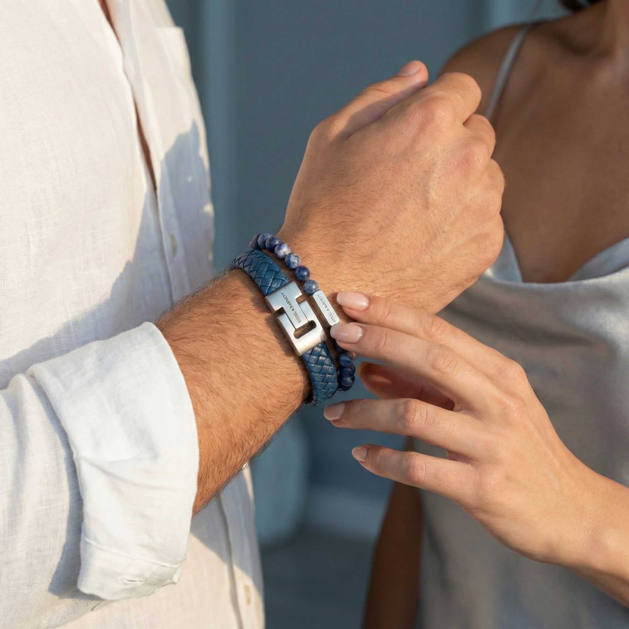 Blue braided leather men’s bracelet with brushed stainless steel clasp and natural stone beads worn on wrist in a lifestyle setting