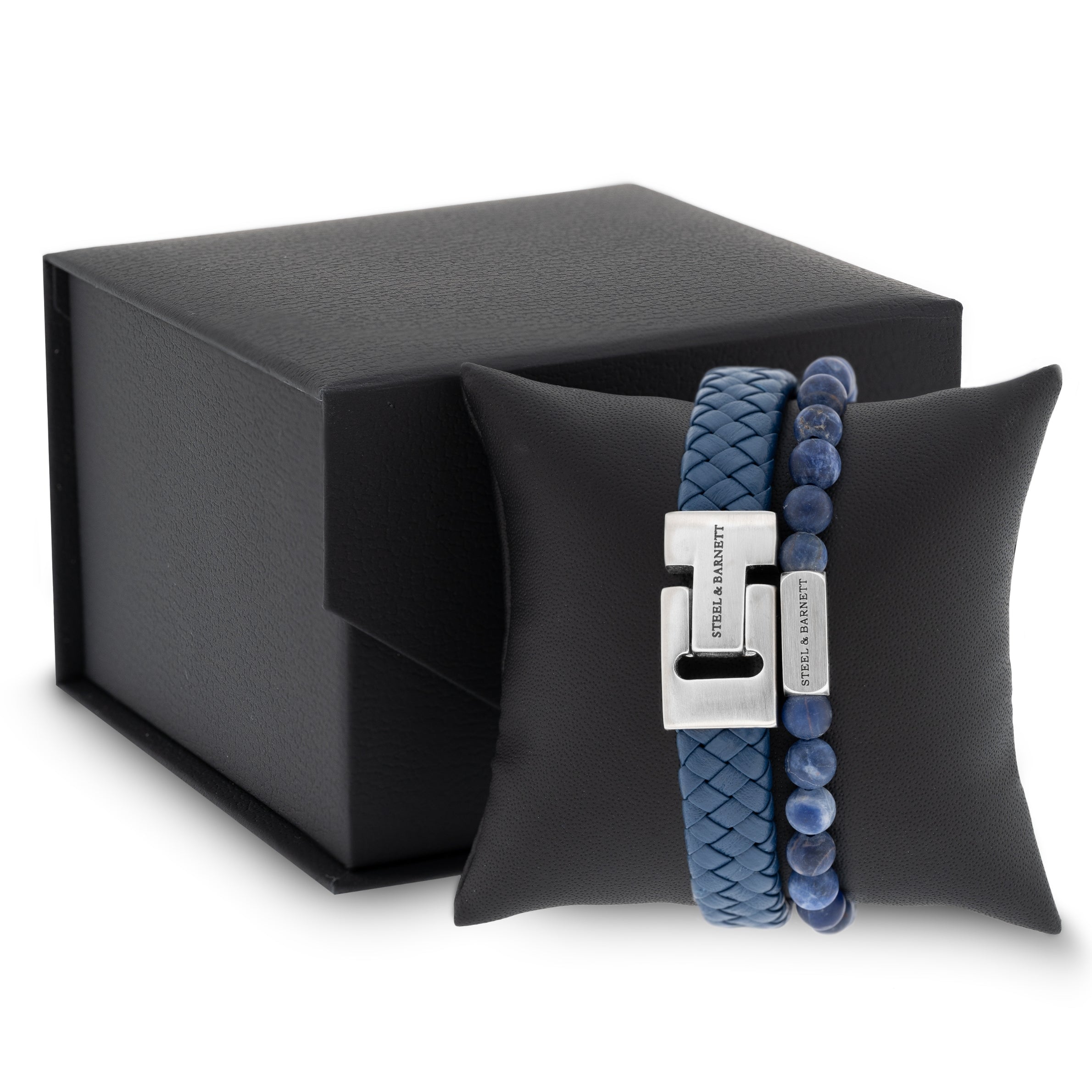 Blue braided leather men’s bracelet with brushed stainless steel clasp and matching beaded bracelet displayed on a black cushion next to a gift box