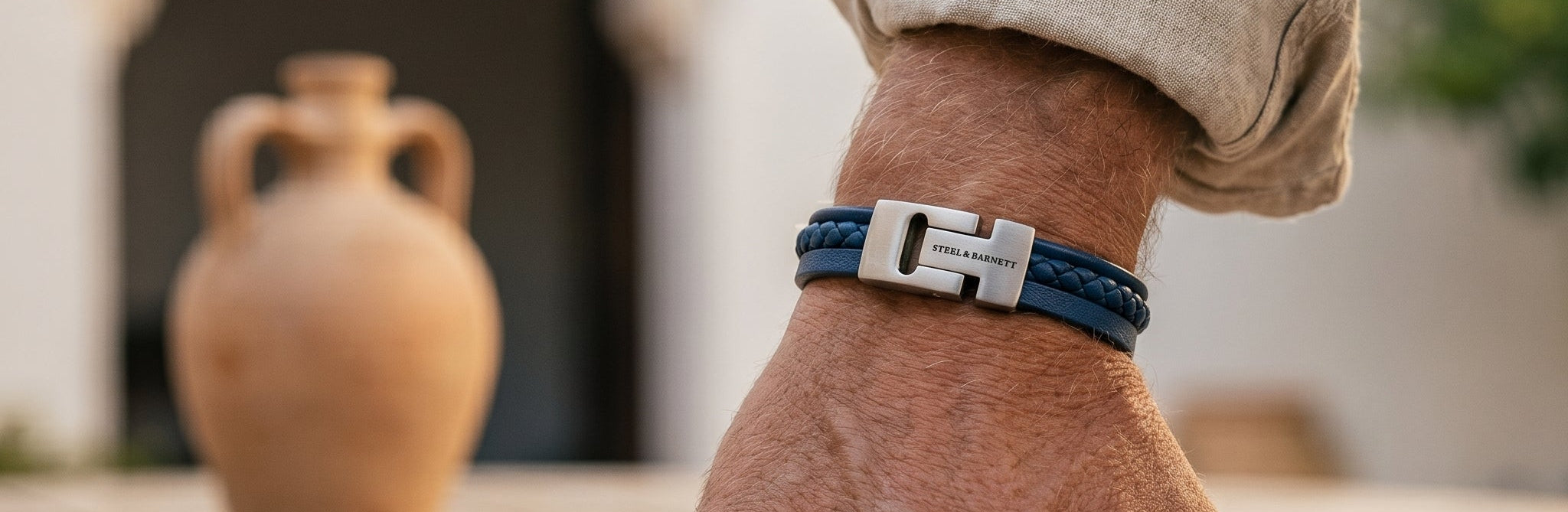 Hand wearing a blue and silver bracelet on a wooden table with a blurred background