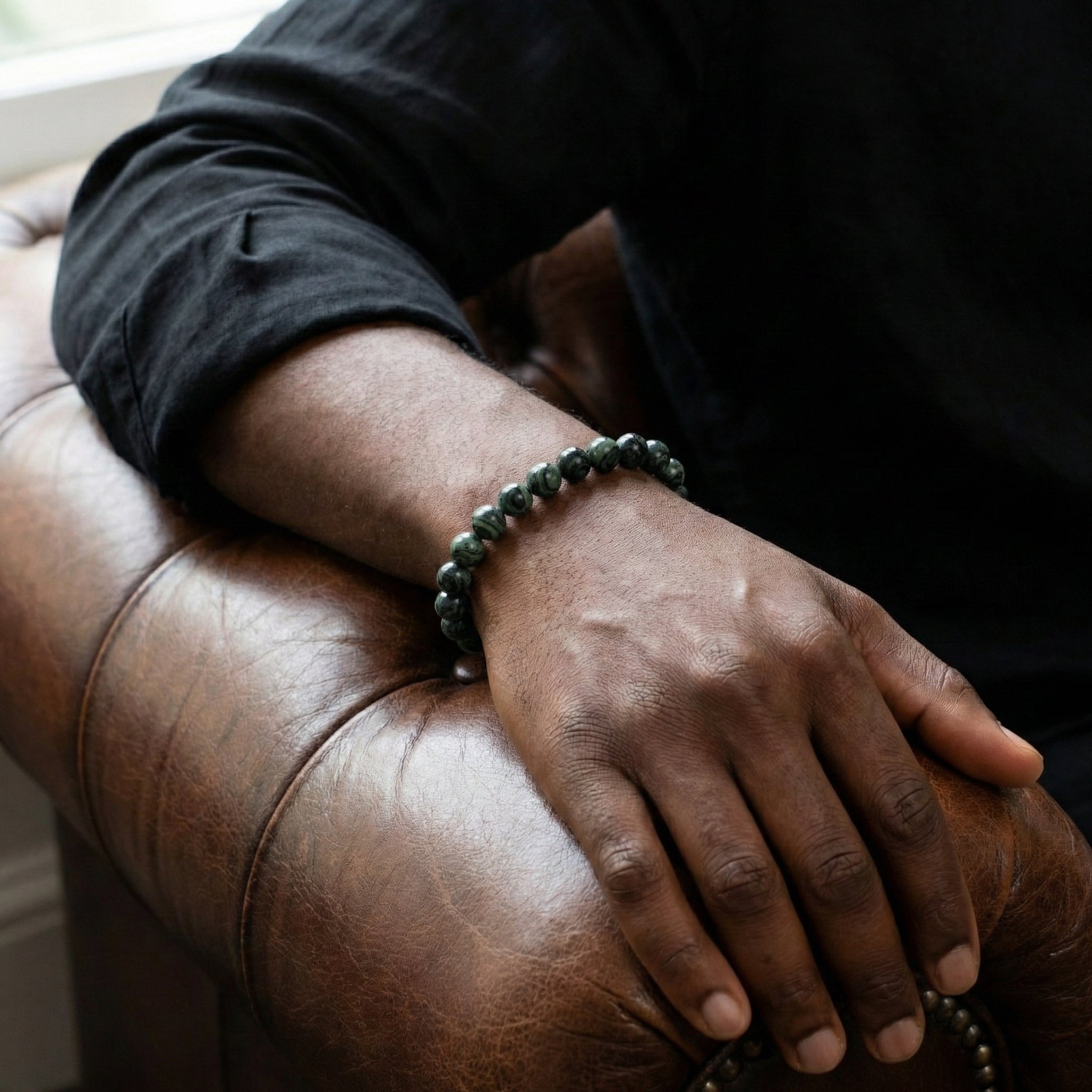 Dark green kambaba stone men's bracelet with beaded design and stainless steel detail worn on wrist