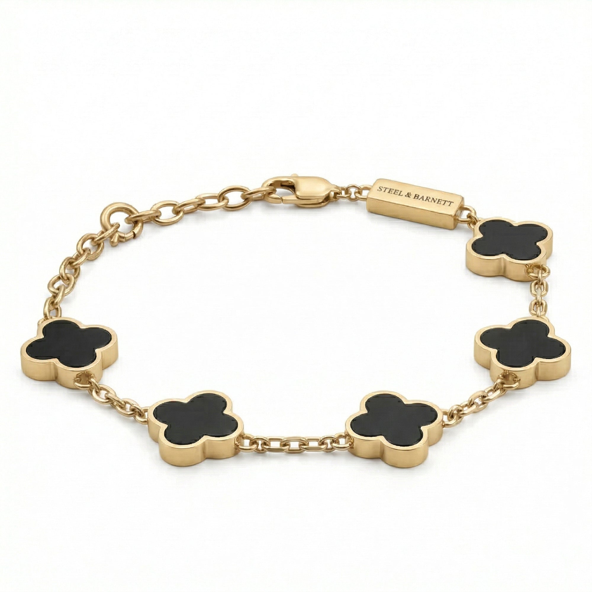 Gold toned men’s bracelet with black clover shaped inlays linked by a chain and lobster clasp on a white background