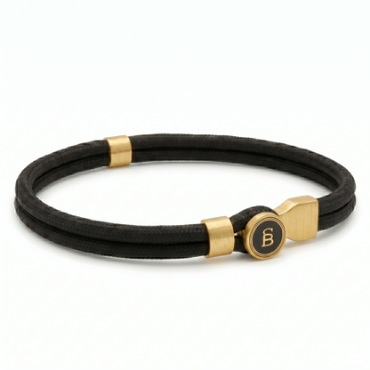 Black braided men's leather bracelet with plated 18K gold clasp and brushed metal details on a white background