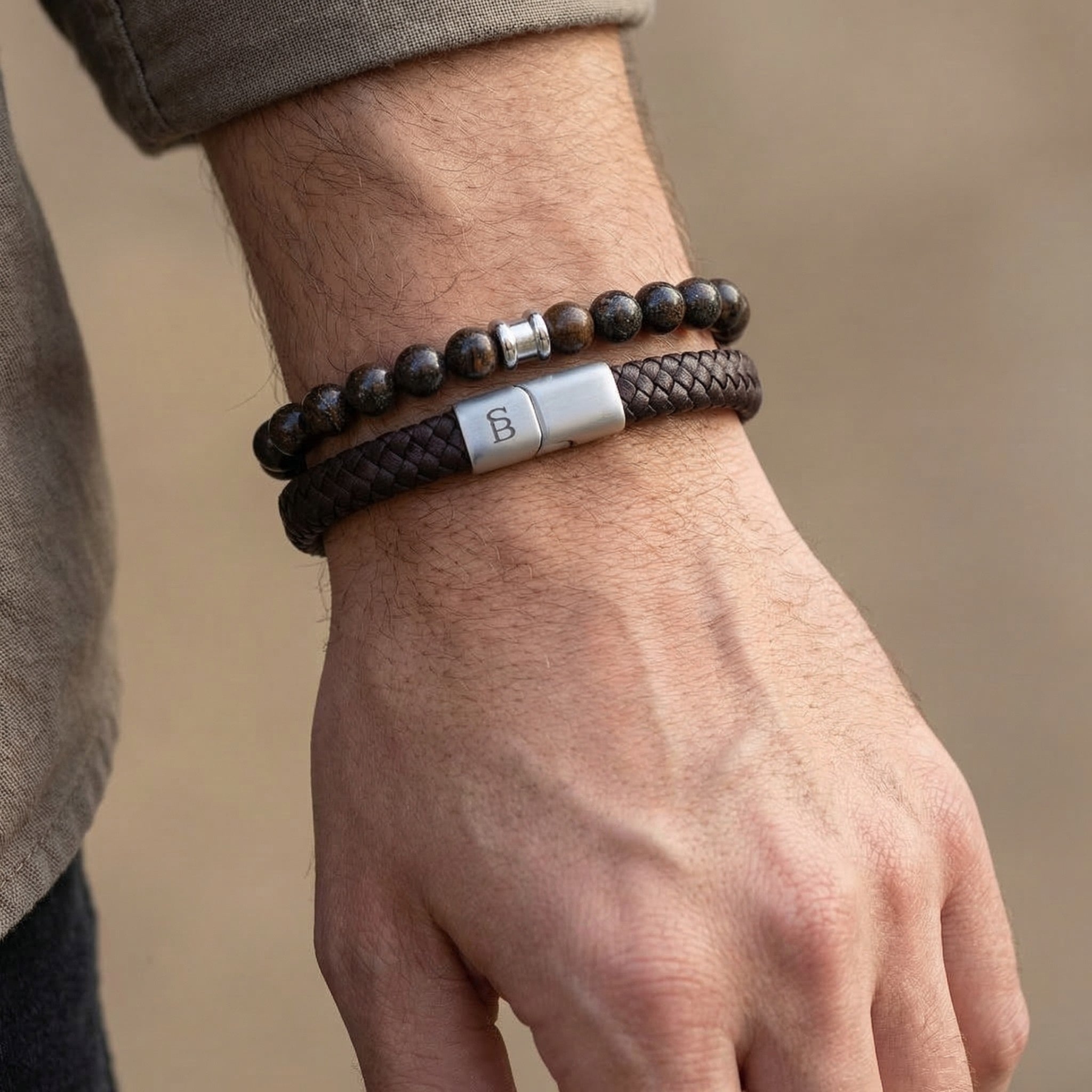Brown leather and natural stone men's bracelets with stainless steel clasp worn in a stacked look on wrist