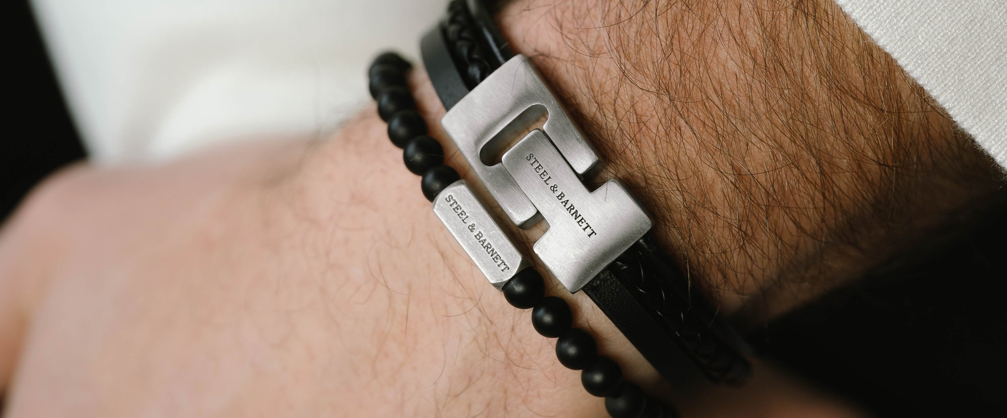 Close-up of a wrist wearing a black beaded bracelet with a metal clasp.