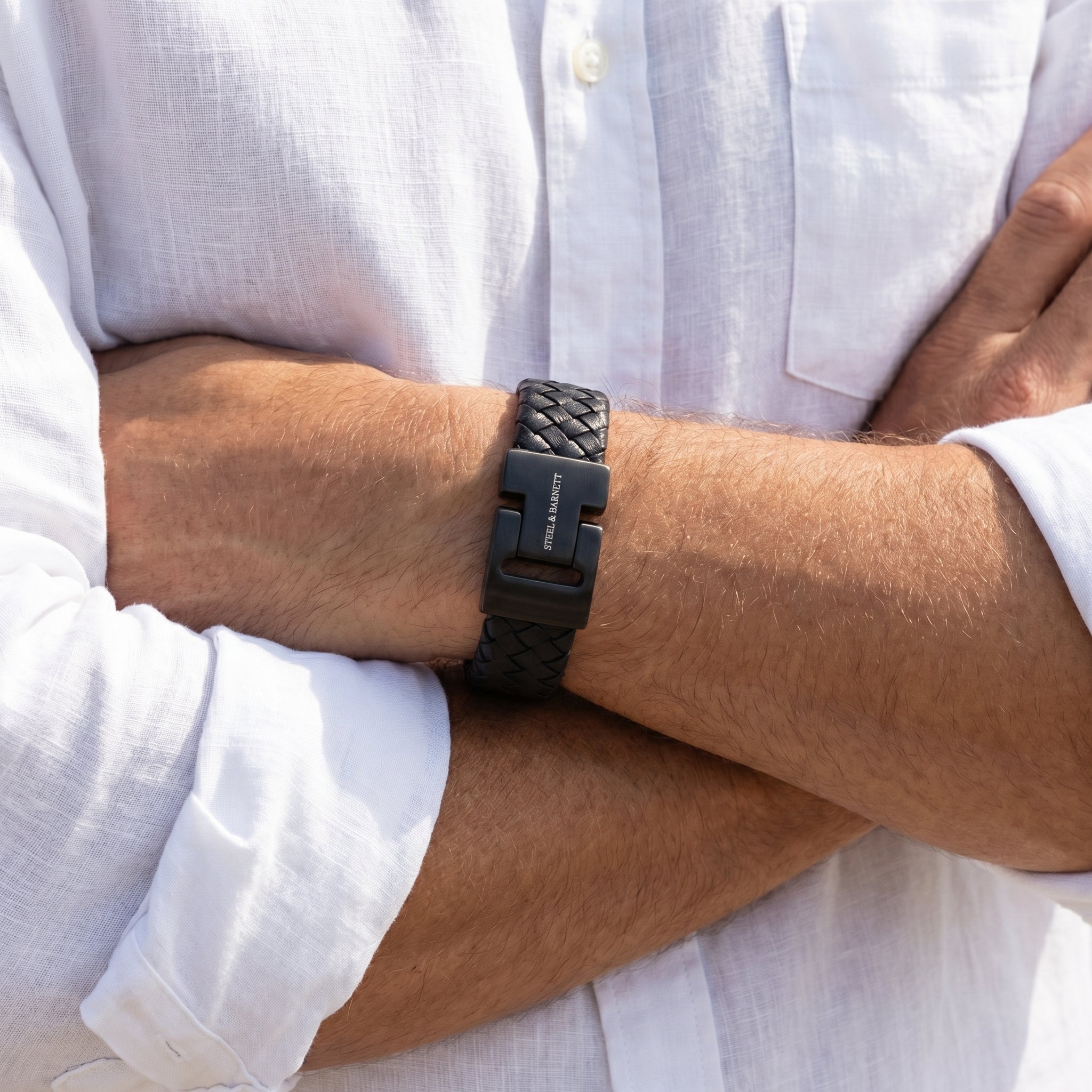 Black braided leather men's bracelet with matte stainless steel magnetic clasp worn on wrist with white shirt