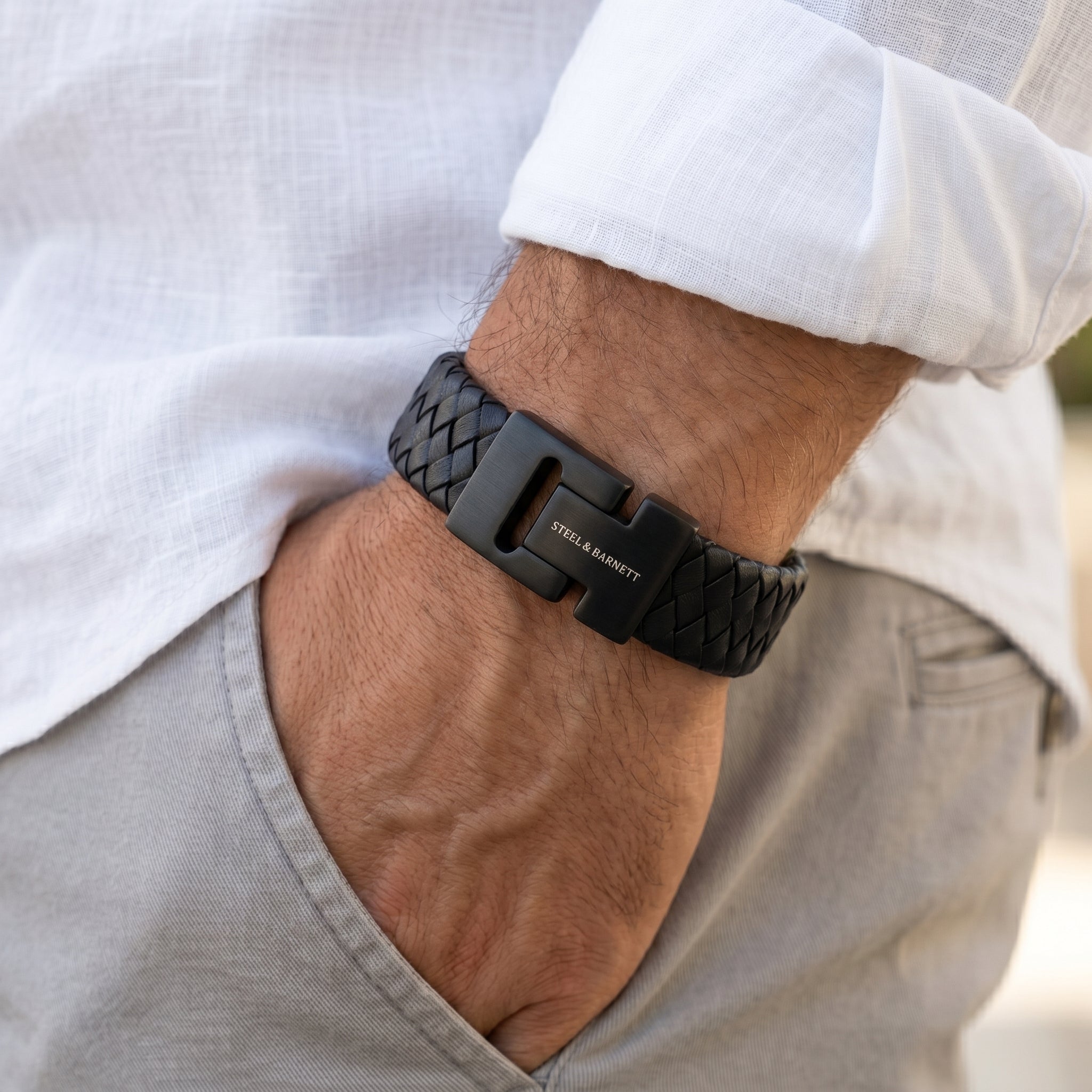 Black braided leather men's bracelet with matte stainless steel magnetic clasp worn on wrist with hand in pocket