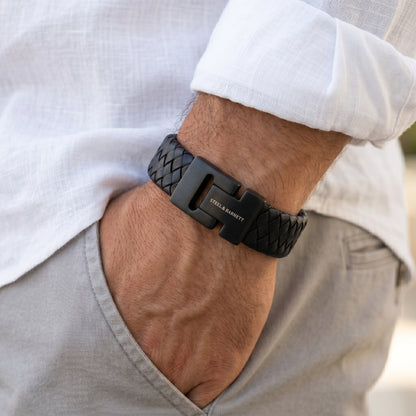 Black braided leather men's bracelet with matte stainless steel magnetic clasp worn on wrist with hand in pocket
