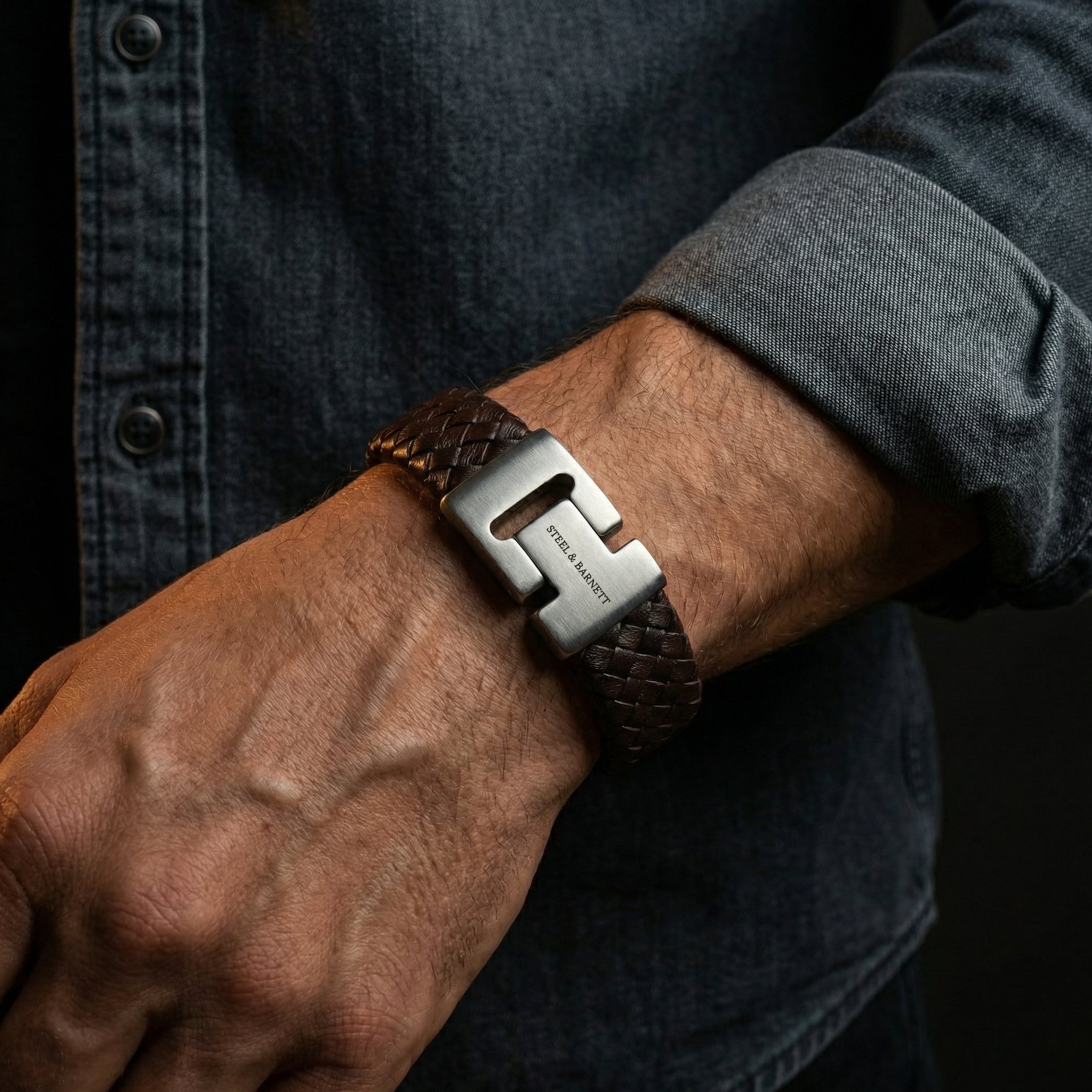 Brown braided leather men’s bracelet with brushed stainless steel clasp shown on wrist in a casual outfit