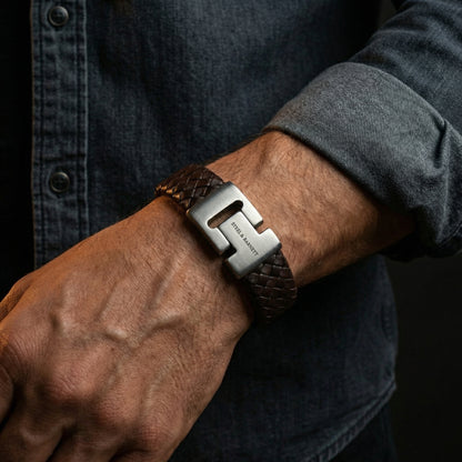 Brown braided leather men’s bracelet with brushed stainless steel clasp shown on wrist in a casual outfit