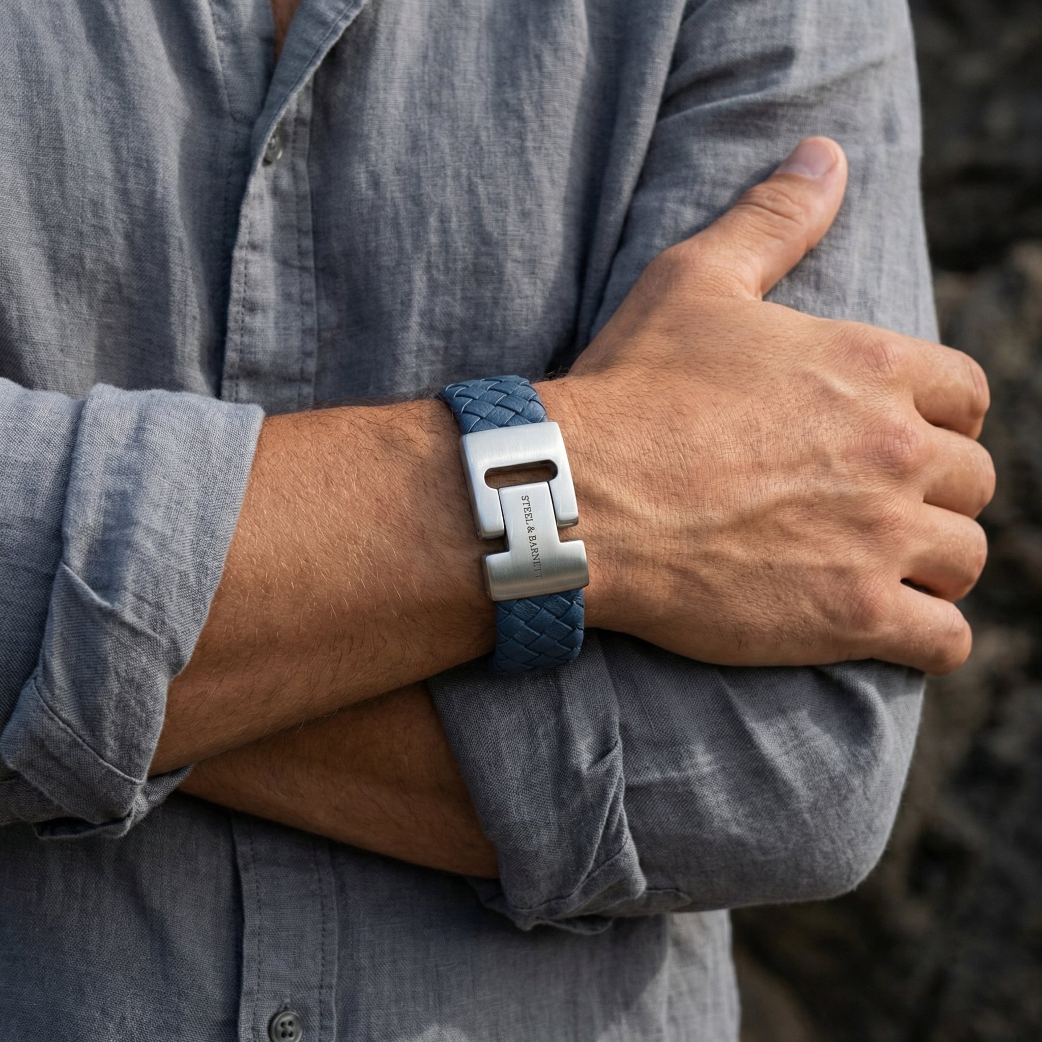 Blue braided leather men’s bracelet with brushed stainless steel clasp worn on wrist with a grey shirt
