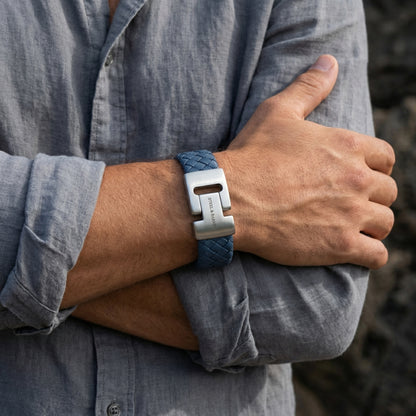 Blue braided leather men’s bracelet with brushed stainless steel clasp worn on wrist with a grey shirt