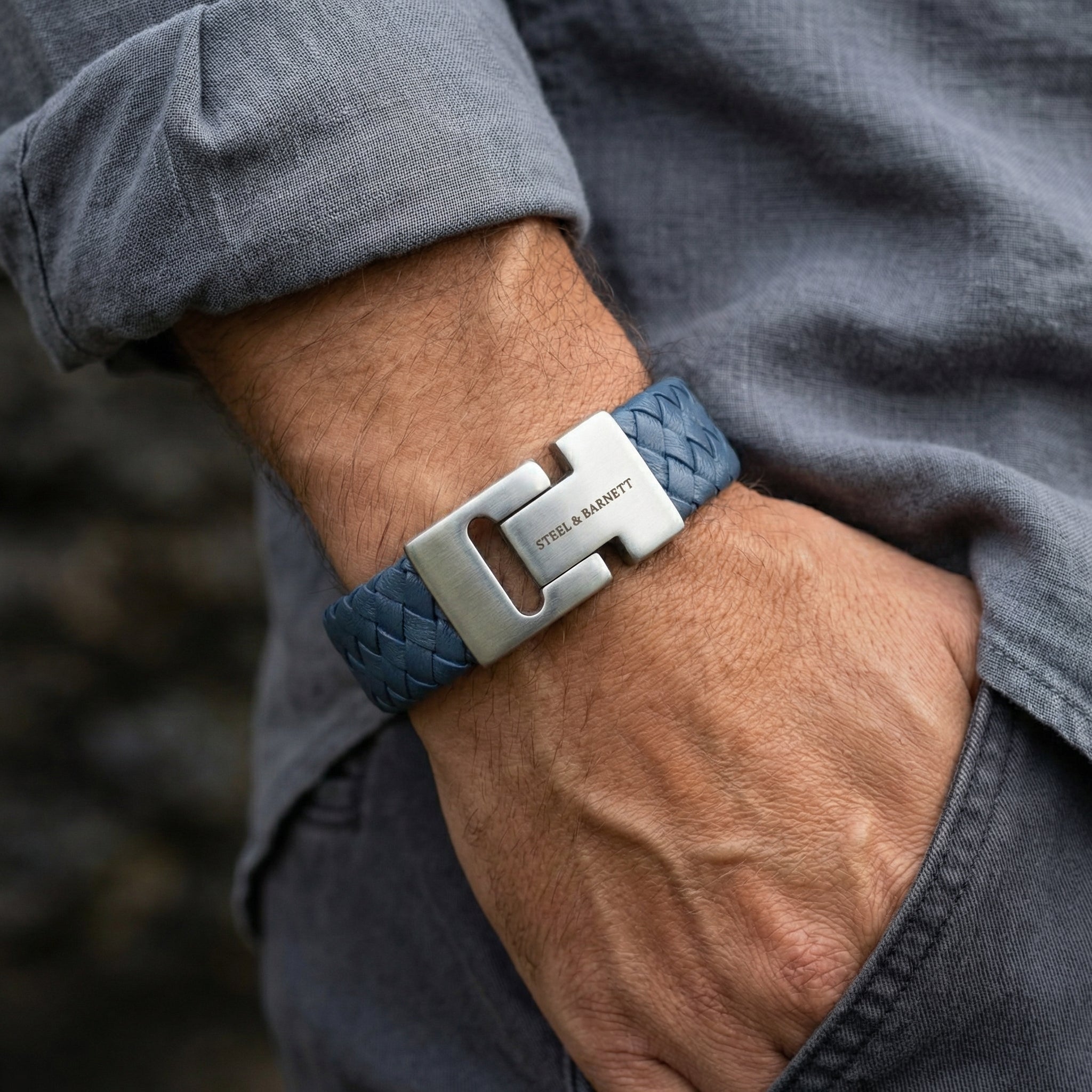Blue braided leather men’s bracelet with brushed stainless steel clasp shown on wrist in a casual setting