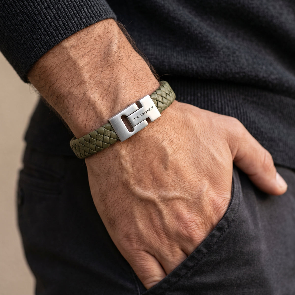 Olive green braided leather men's bracelet with a brushed stainless steel clasp worn on a wrist