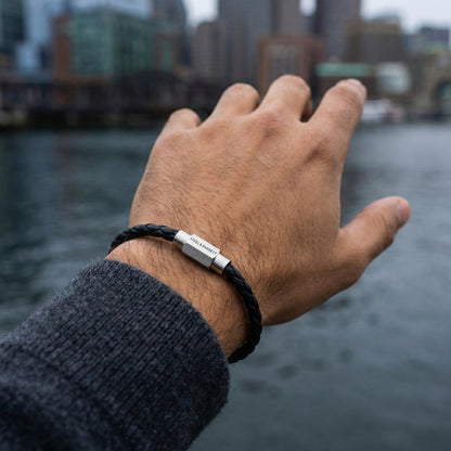Black braided leather men’s bracelet with brushed stainless steel clasp worn on wrist by the water