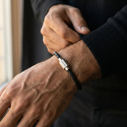 Black braided leather men’s bracelet with brushed stainless steel magnetic clasp shown on wrist in close up