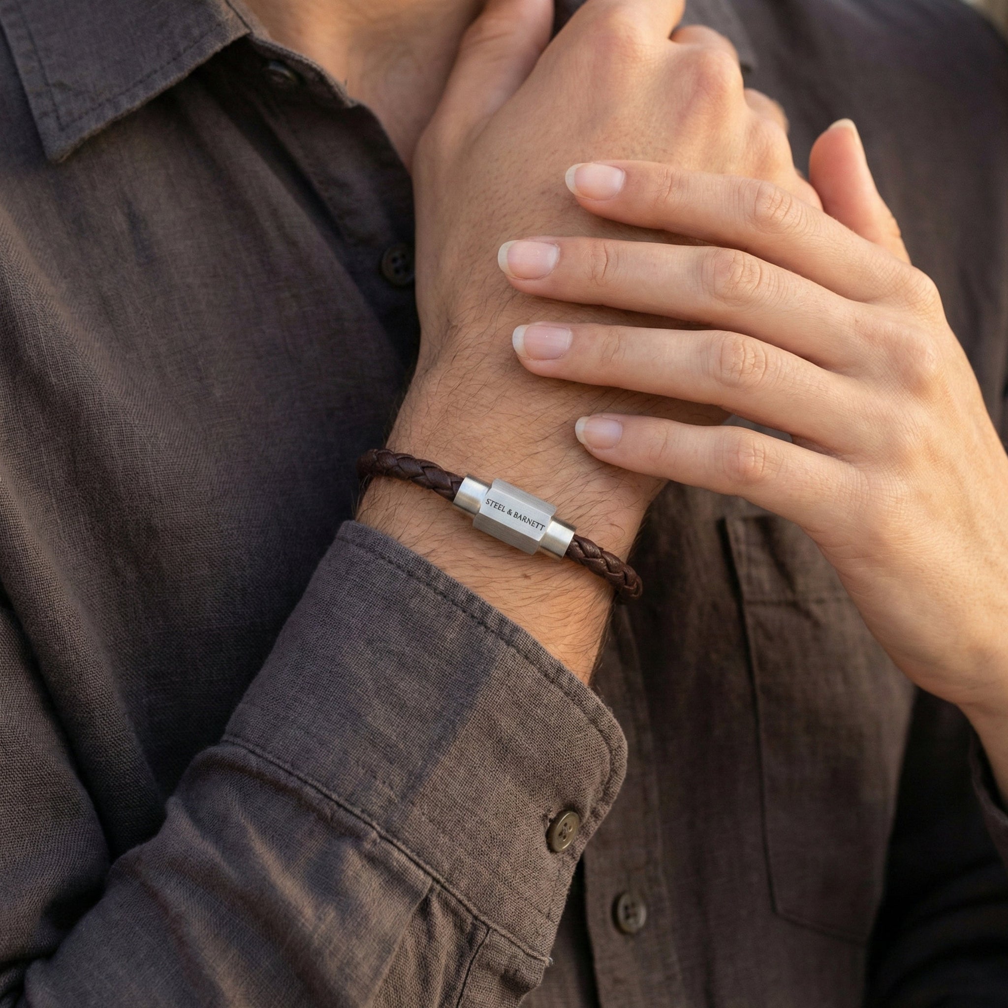 Brown braided leather men’s bracelet with brushed stainless steel magnetic clasp on stacked stone surface