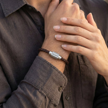 Brown braided leather men’s bracelet with brushed stainless steel magnetic clasp on stacked stone surface